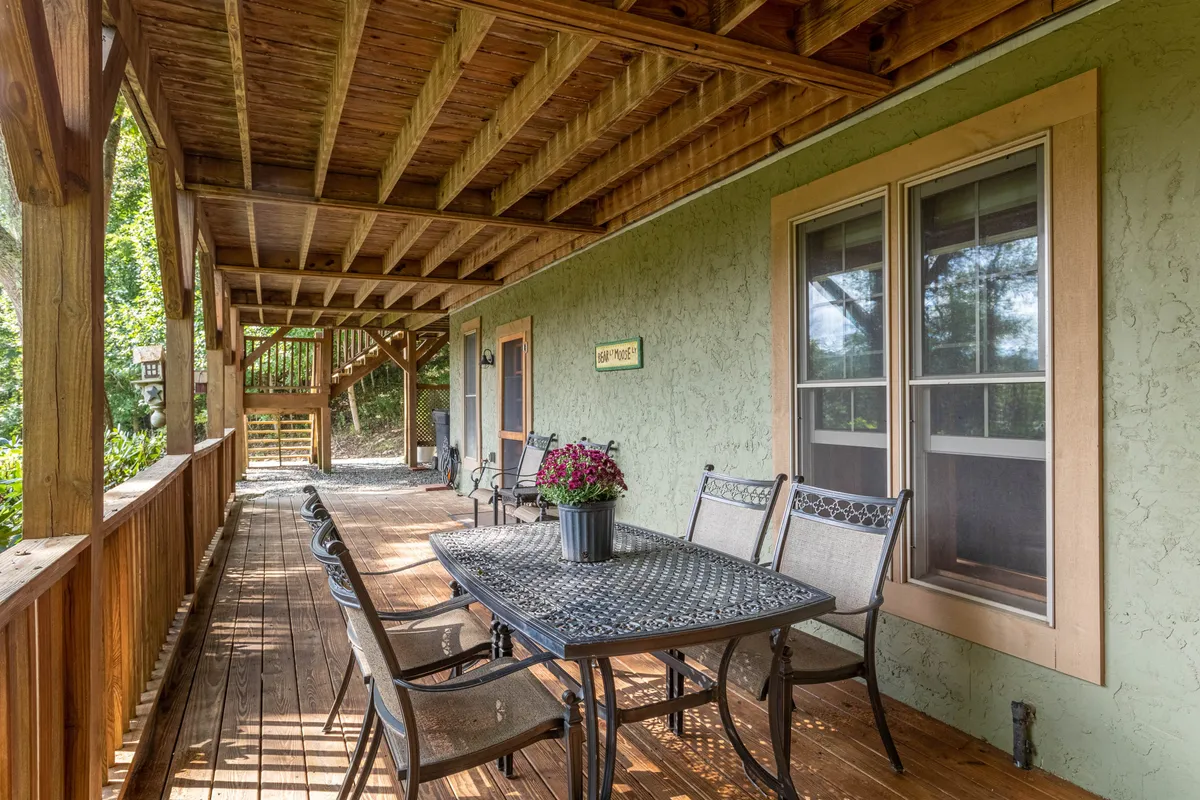 A welcoming exterior view showcasing a dining table set against flower pots, wooden beams, and windows, ideal for social gatherings. The setup hints at festive celebrations, morning brunches, or sunset dinners, capturing the playful spirit of group retreats.