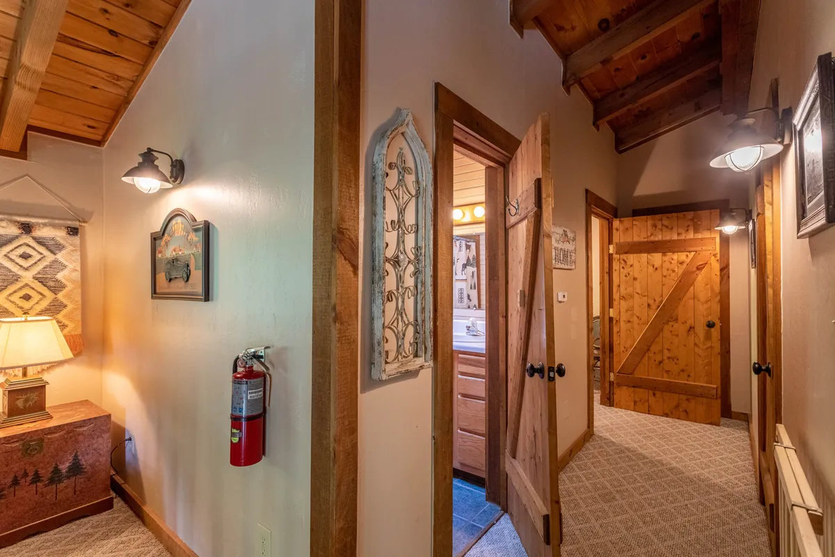 A cozy hallway with wooden beams, decorative wall art, and wooden doors, giving a rustic lodge ambiance. Although primarily an interior view, the scene suggests a welcoming entry point and sets the tone for arrival after outdoor activities.